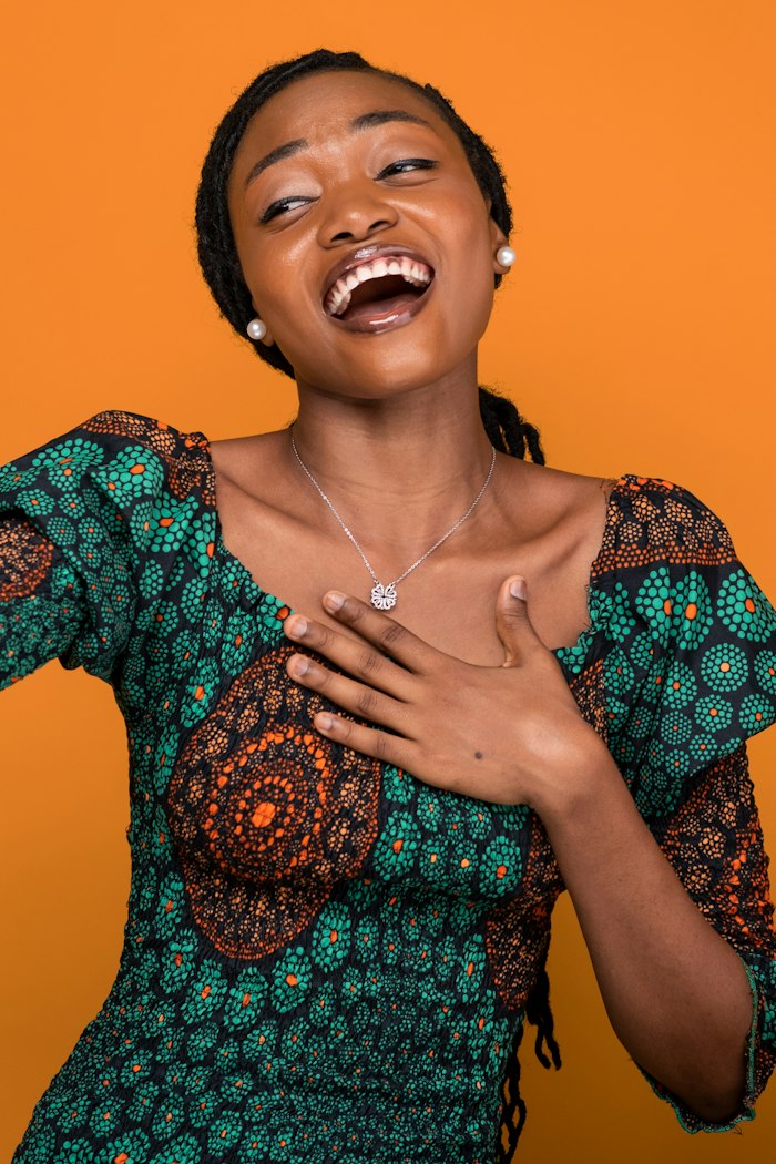 A woman laughing warmly, hand on her chest